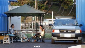 A parked Toyota vehicle, a covered outdoor seating area, and a blue building in the background.