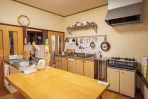 Una cocina con armarios de madera, un lavamanos de acero inoxidable, una estufa y varios utensilios de cocina colgados en la pared.