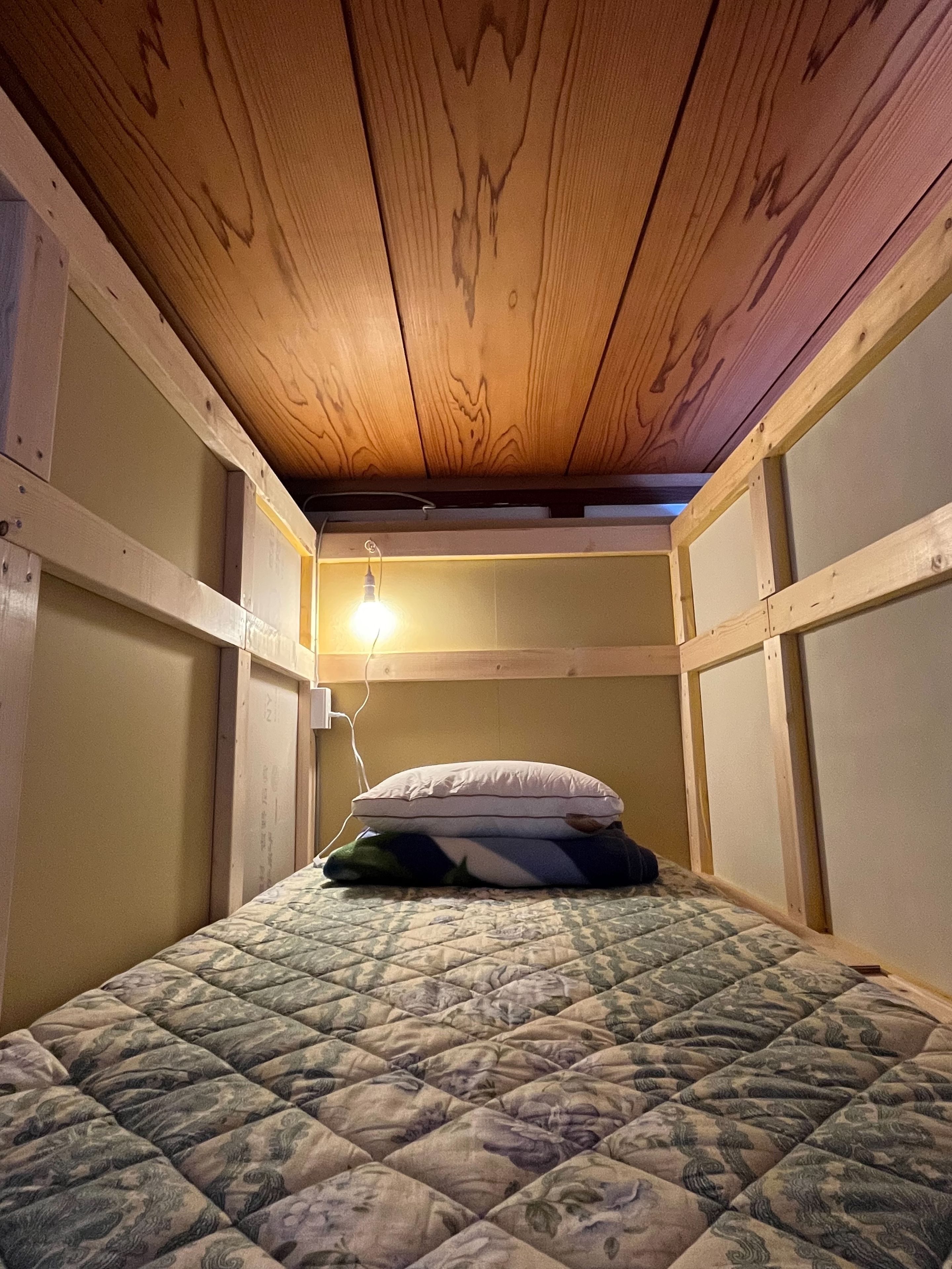 Una cama litera con colchón acolchado, una almohada y un aplique de pared.