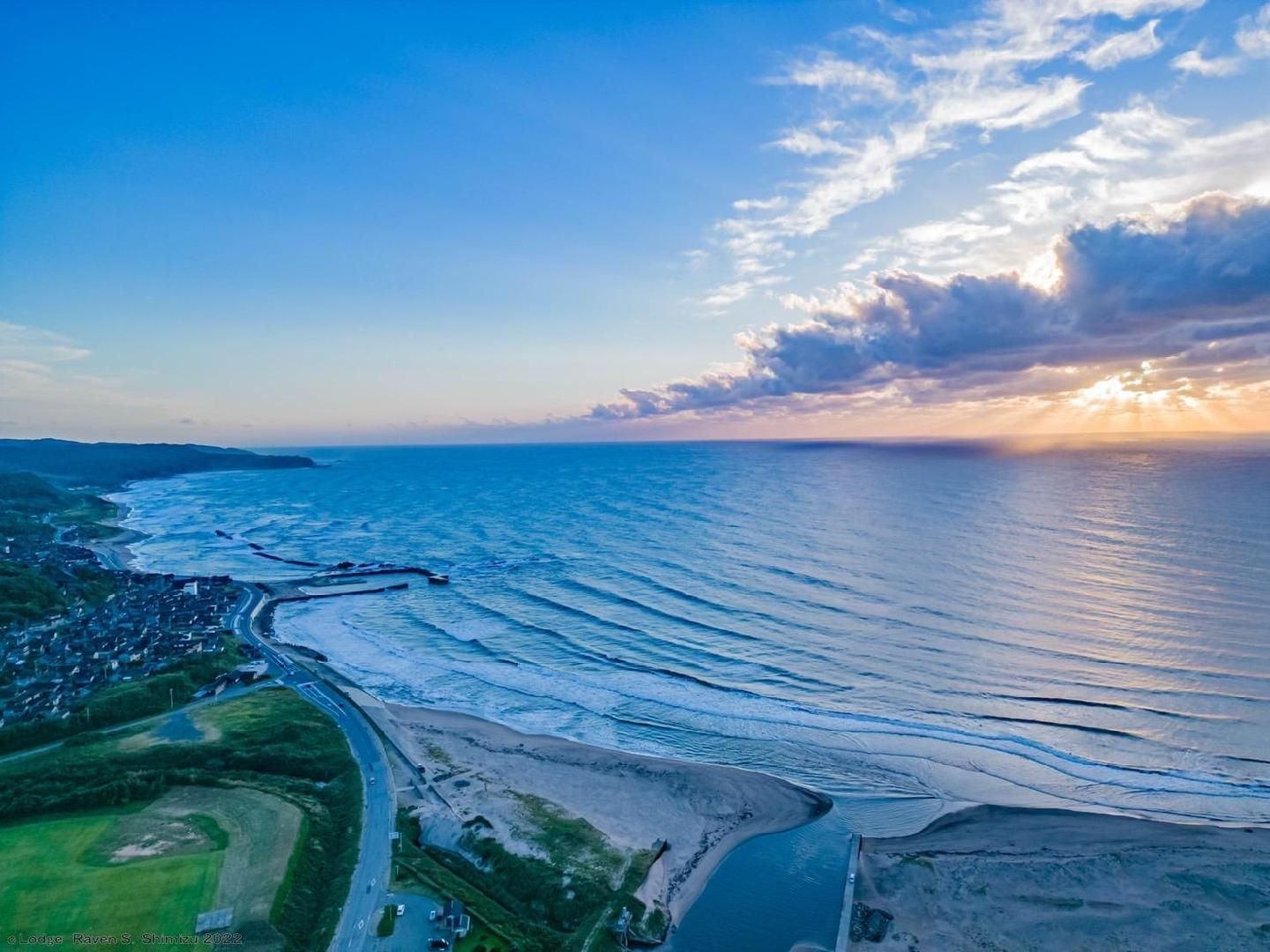 An aerial view of a coastal area with a road, beach, and ocean.