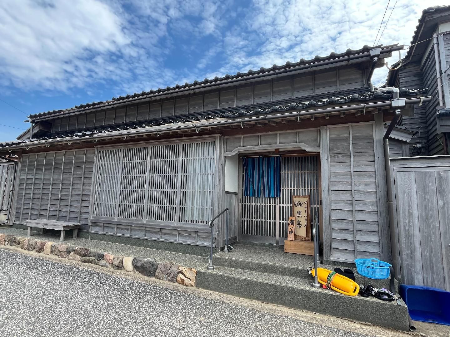 En traditionel japansk bygning med træfacade, et tag med fliser og en lille veranda.