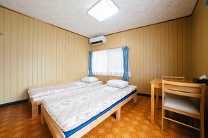 Ein Zimmer mit zwei Betten, einem Schreibtisch und einem Stuhl.