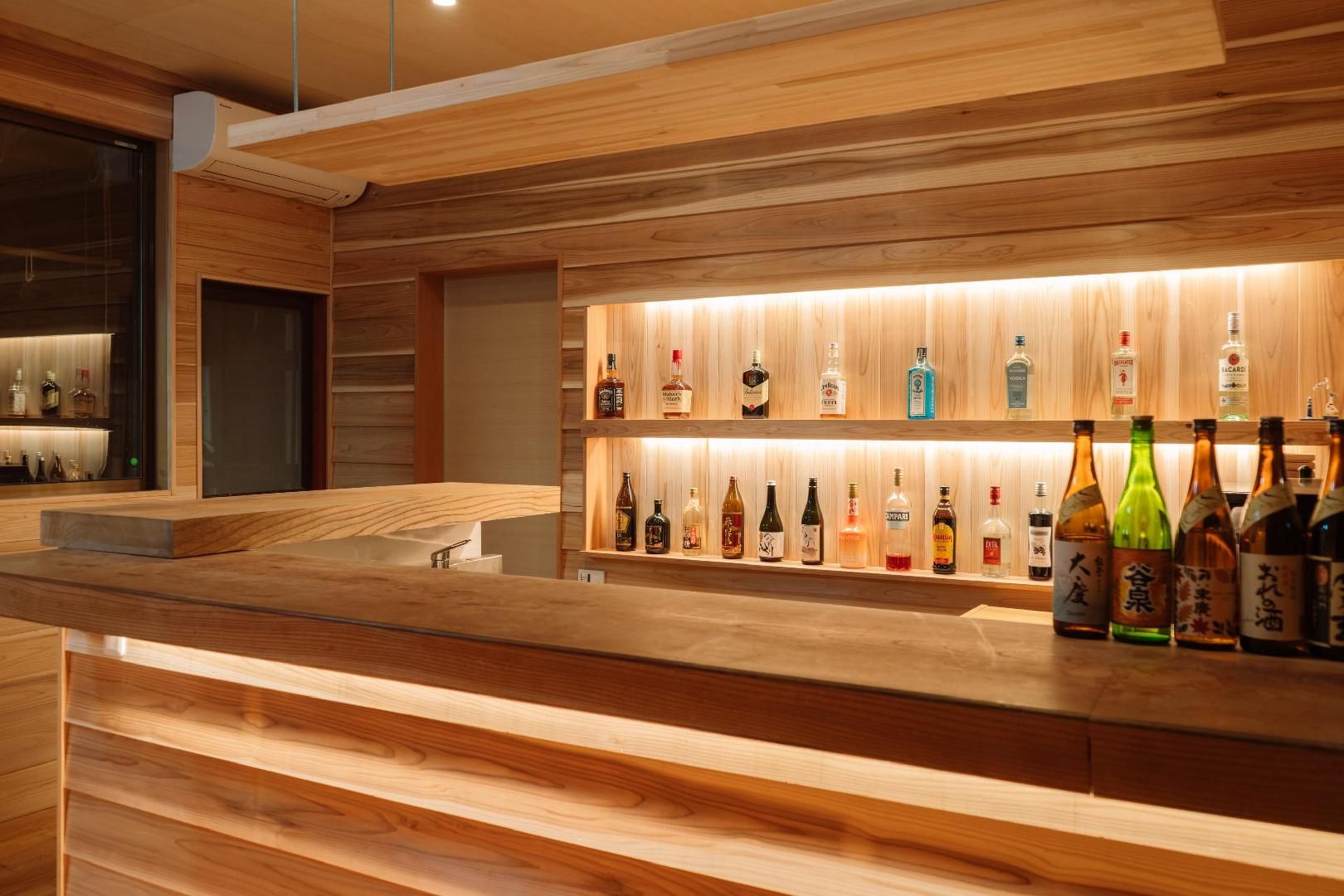 Una zona de bar con estantes de madera que exhiben varias botellas de licor.