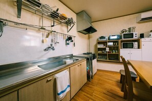 Una cocina compacta con un lavamanos de acero inoxidable, armarios de madera, una estufa a gas y un microondas.