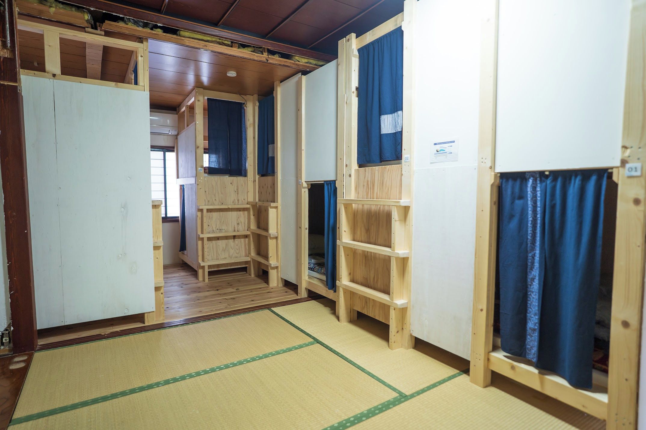 Una habitación con literas de madera, esteras de tatami y un armario de madera.