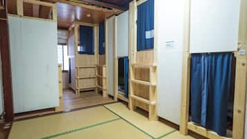 Una habitación con literas de madera, esteras de tatami y un armario de madera.