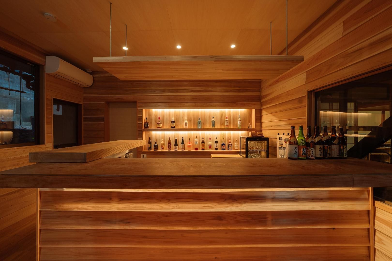 A bar area with wooden paneling and a shelf of various liquor bottles.