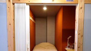 A bedroom with a bed, a desk with a lamp, and a wooden ceiling structure. - El Amarillo Self Check-in Hostel (Fukushima)