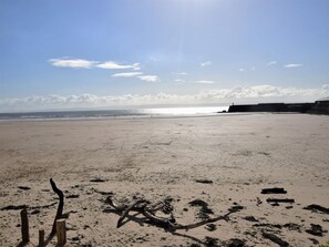 Ein Strand mit einer Holzzahlung, einem treibholzstück und einer fernen Küste.