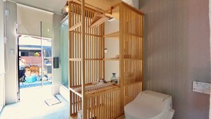 A bathroom with a toilet, a wooden partition, and a glass door leading to a patio area. - Polaris (Takashima)