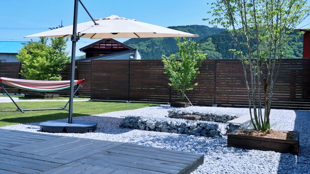 A wooden deck, a hammock, a small tree, and a wooden fence in a backyard. - Polaris (Takashima)