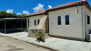 A modern building with a tiled roof, a covered entrance, and a stone plaque. - Ishigaki Villa Musubu (Ishigaki)