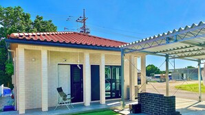 A small building with a tiled roof, a covered patio area, and a grassy lawn. - Ishigaki Villa Musubu (Ishigaki)