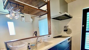 A modern kitchen with a large island, wooden flooring, and a built-in oven. - Ishigaki Villa Musubu (Ishigaki)