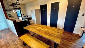 A compact kitchen with a wooden table and bench, a microwave, and a refrigerator. - Ishigaki Villa Musubu (Ishigaki)