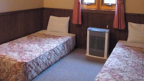A room with two beds, a window with curtains, a wall-mounted heater, and a decorative wall piece. - Pension Mogu (Shinano)