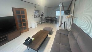 Una sala de estar con sofá, mesa de centro, televisor y un comedor con sillas y mesa.