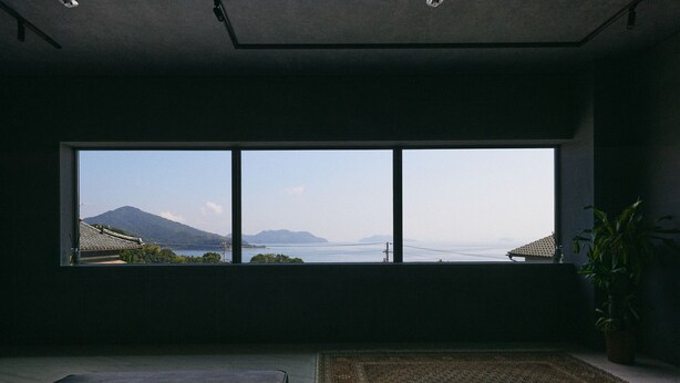 Una habitación con un ventanal grande que da a un paisaje montañoso y un cuerpo de agua.