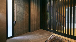 Un interior moderno con una puerta de madera, un tapete estampado y vistas a través de un ventanal vertical.
