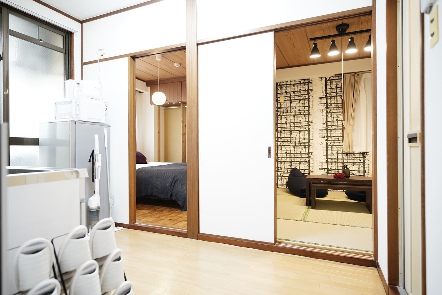 A modern room with a bed, a desk, and a view through a shoji screen.
