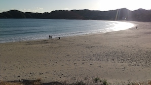 Una playa con vista despejada al agua, una orilla arenosa y colinas distantes.