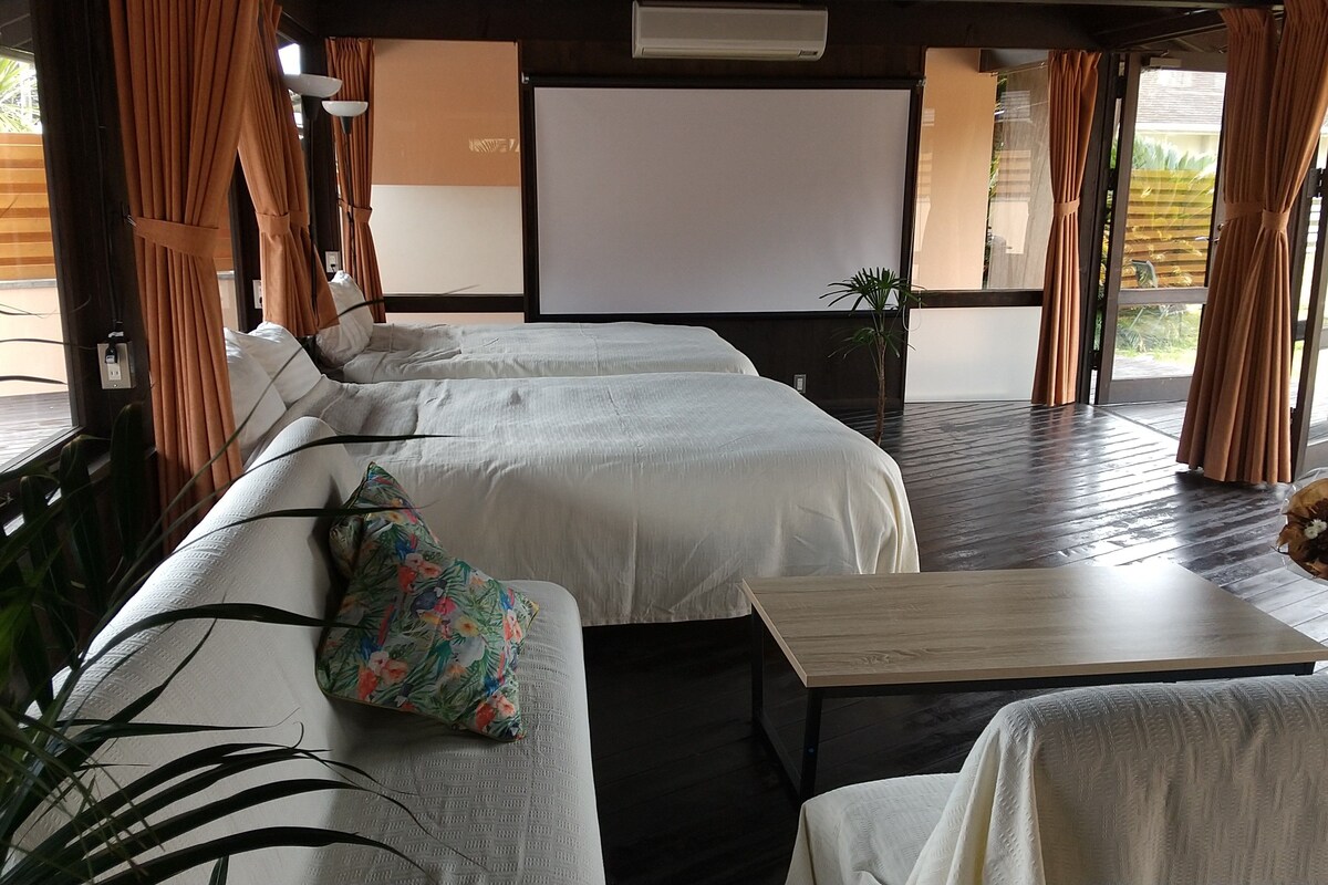 A room with a sofa, a small table, and a bed with a white bedspread.