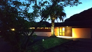 Una casa moderna con una entrada bien iluminada, rodeada de árboles.