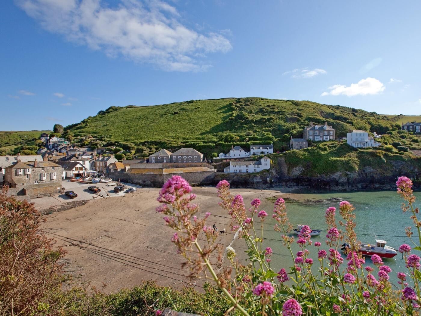 A coastal town with buildings on a hillside, a sandy beach, and boats in the water.