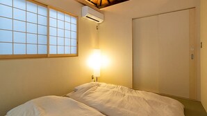 A room with a bed, a window with a grid pattern, an air conditioning unit, and a wardrobe. - Trawl (Kamakura)