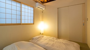 Habitació amb llit, finestra amb un disseny de graella, aire condicionat i un armari.