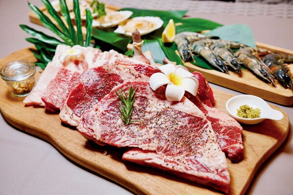 A wooden cutting board with raw meat, garnishes, and seafood. - Glampng Village Seagrand (Matsuura)