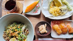 Un àpat amb diversos plats, incloent un bol de noodles, un plat de sashimi i un petit bol de verdures envinagrades.