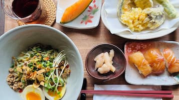 A meal with various dishes including a bowl of noodles, a plate of sashimi, and a small bowl of pickled vegetables.