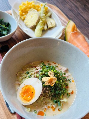A bowl of soup with noodles, a boiled egg, and green onions on a wooden table.