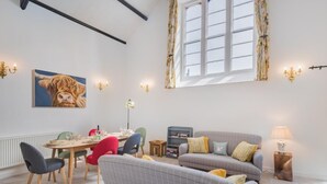 A modern living room with a dining table, chairs, a sofa, a lamp, and a painting of a cow. - 3 Bed in Windermere (oc-sz469) (Windermere)
