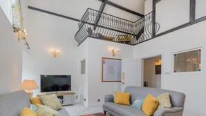 A living room with two grey sofas, a colorful rug, a TV, and a staircase. - 3 Bed in Windermere (oc-sz469) (Windermere)