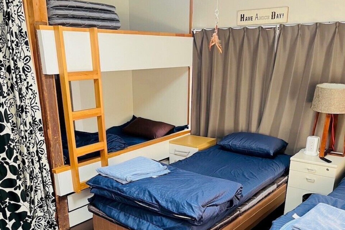 Une chambre avec des lits superposés, une table de chevet avec une lampe et un panneau indiquant : « Passez une bonne journée ! »