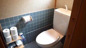 Un baño pequeño con inodoro, dispensador de toallas de papel y rollos de papel higiénico.