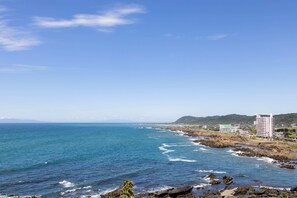 A coastal view with a hotel, rocky shoreline, and ocean waves. - Tavistar (Minamiboso)