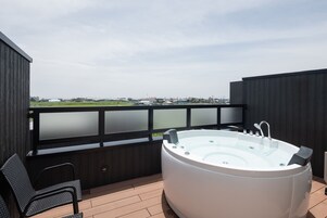 Jacuzzi en terraza de madera con vista a un paisaje urbano.