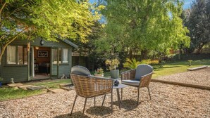 A cozy outdoor seating area with wicker chairs and a table, a small shed with a door, and a well-maintained garden. - 1 Bed in Sandown (oc-85248) (Sandown)