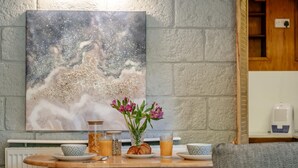 A breakfast setup with a table, chairs, a painting, and a vase with flowers. - 1 Bed in Sandown (oc-85248) (Sandown)