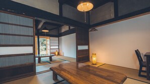 A traditional Japanese room with tatami flooring, a wooden table, and a low ceiling with exposed beams. - Tsumugiyado Fuji (Fujieda)