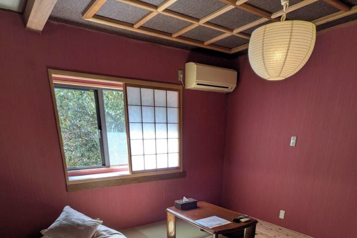 A room with a bed, a small table, and a window.