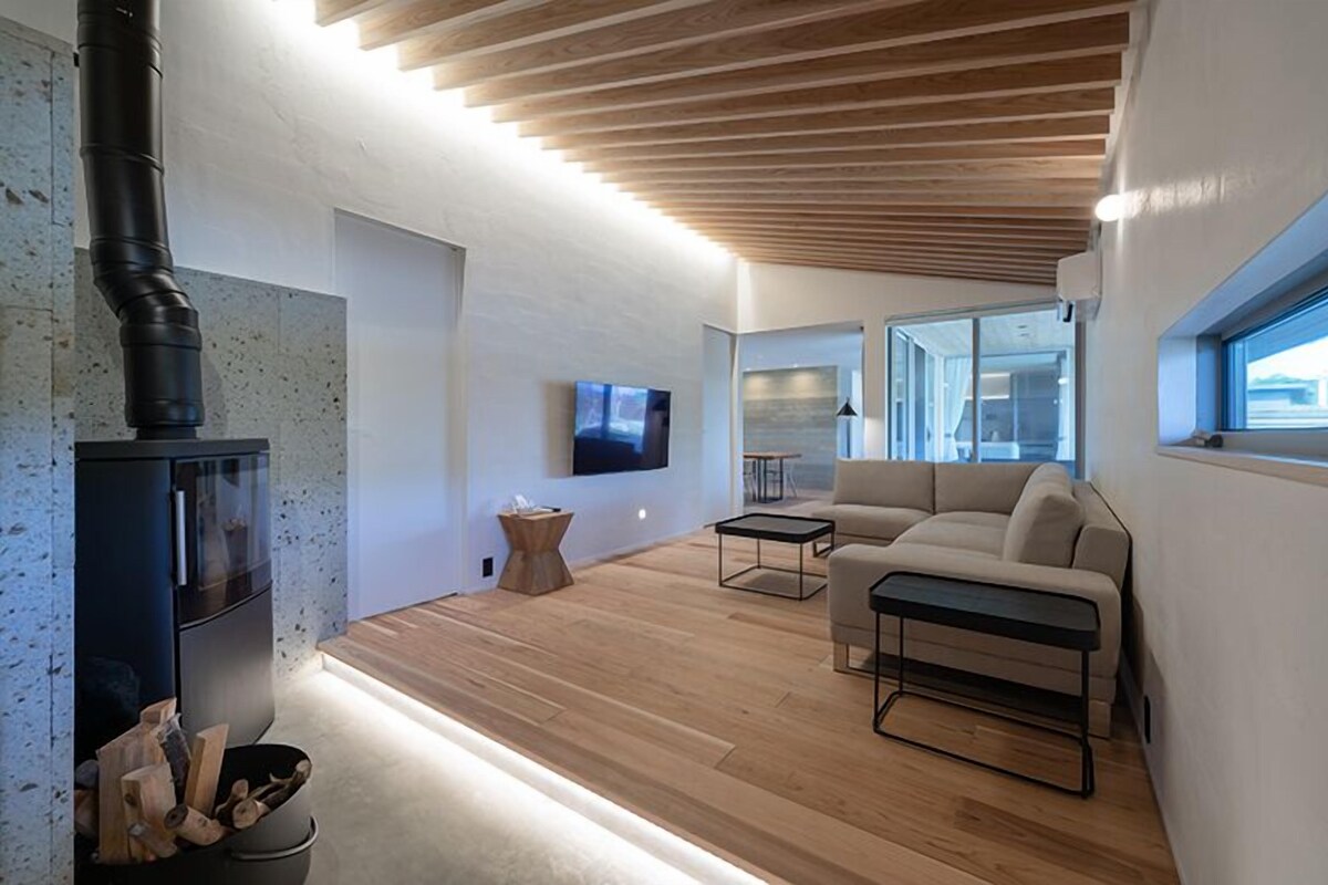Una sala de estar moderna con chimenea, un sofá, una mesa de centro y un televisor montado en la pared.