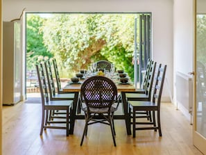 Een eetgedeelte met een tafel voor vier personen, omringd door stoelen, met uitzicht op groen.