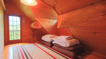 Una habitación acogedora tipo cabaña con techo inclinado, un ventanal grande y una cama con almohadas.