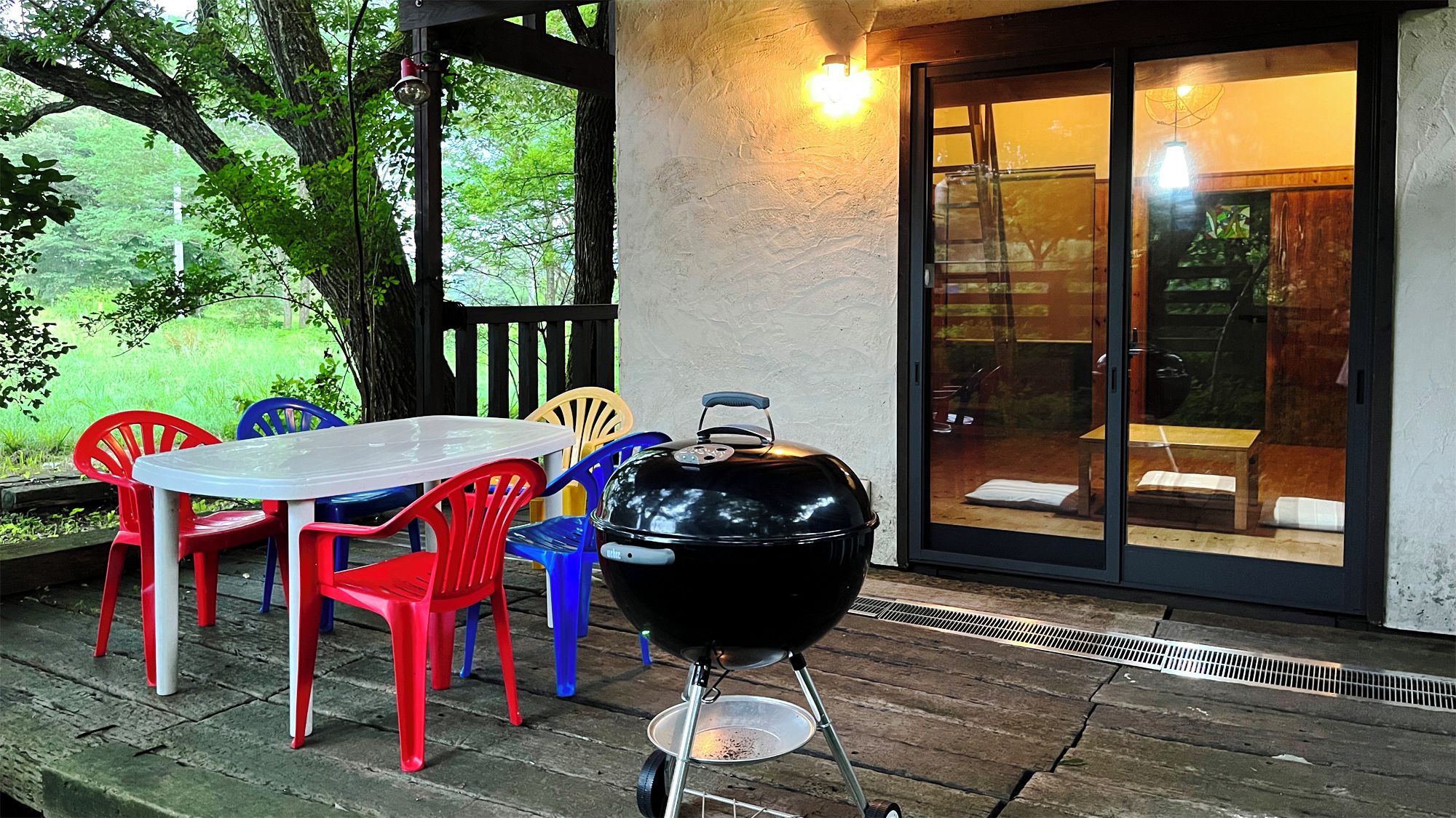 An outdoor patio with a table and chairs, a barbecue grill, and a sliding glass door leading to an interior space.