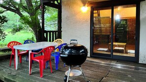 An outdoor patio with a table and chairs, a barbecue grill, and a sliding glass door leading to an interior space.