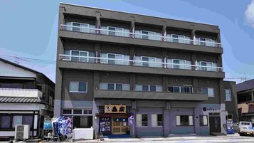 Un edificio de varios pisos con techo plano, varios balcones y una fachada comercial en la planta baja.